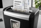 Modern office paper shredder with cross-cut blades destroying confidential business documents into small particles
