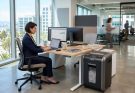 Modern office paper shredder standing next to a corporate desk.